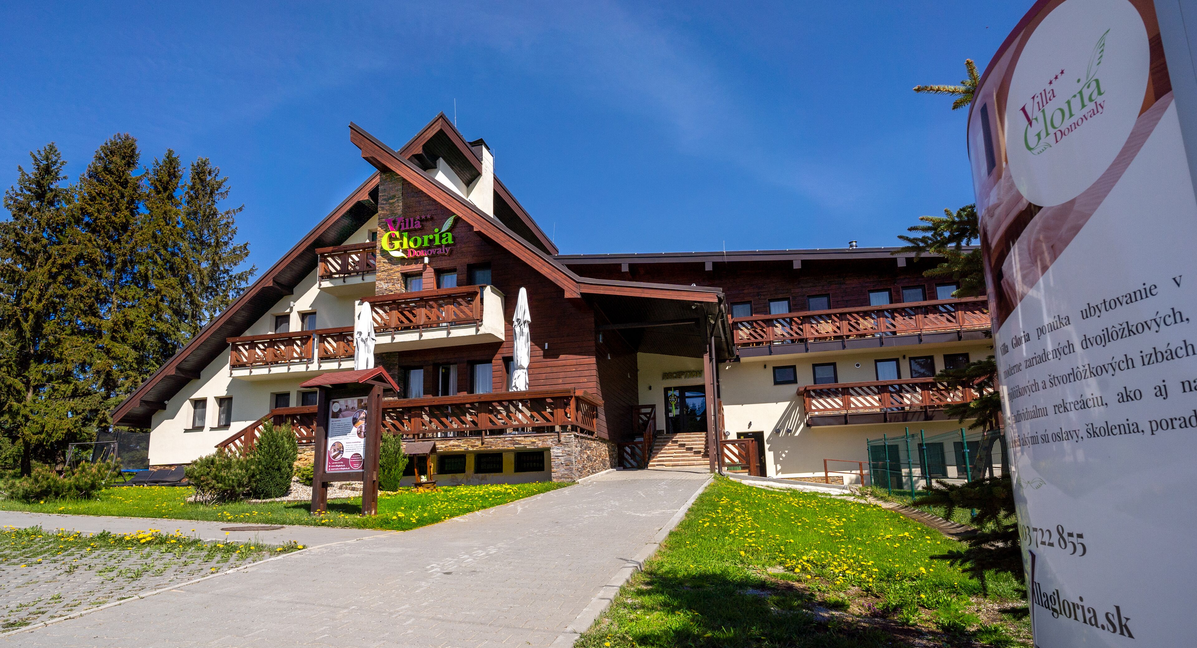 A multi-story building with a prominent sign for Villa Gloria Donovaly.