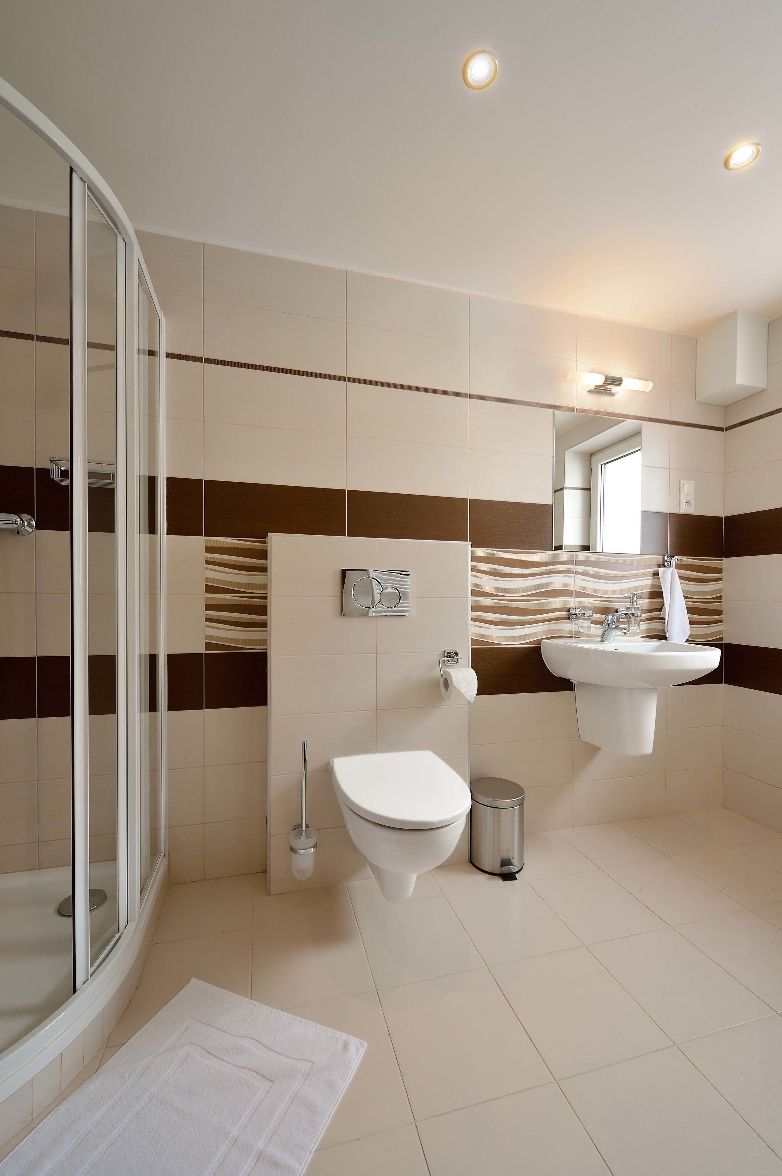 A modern bathroom with a glass shower enclosure, a toilet, a sink, and a mirror.
