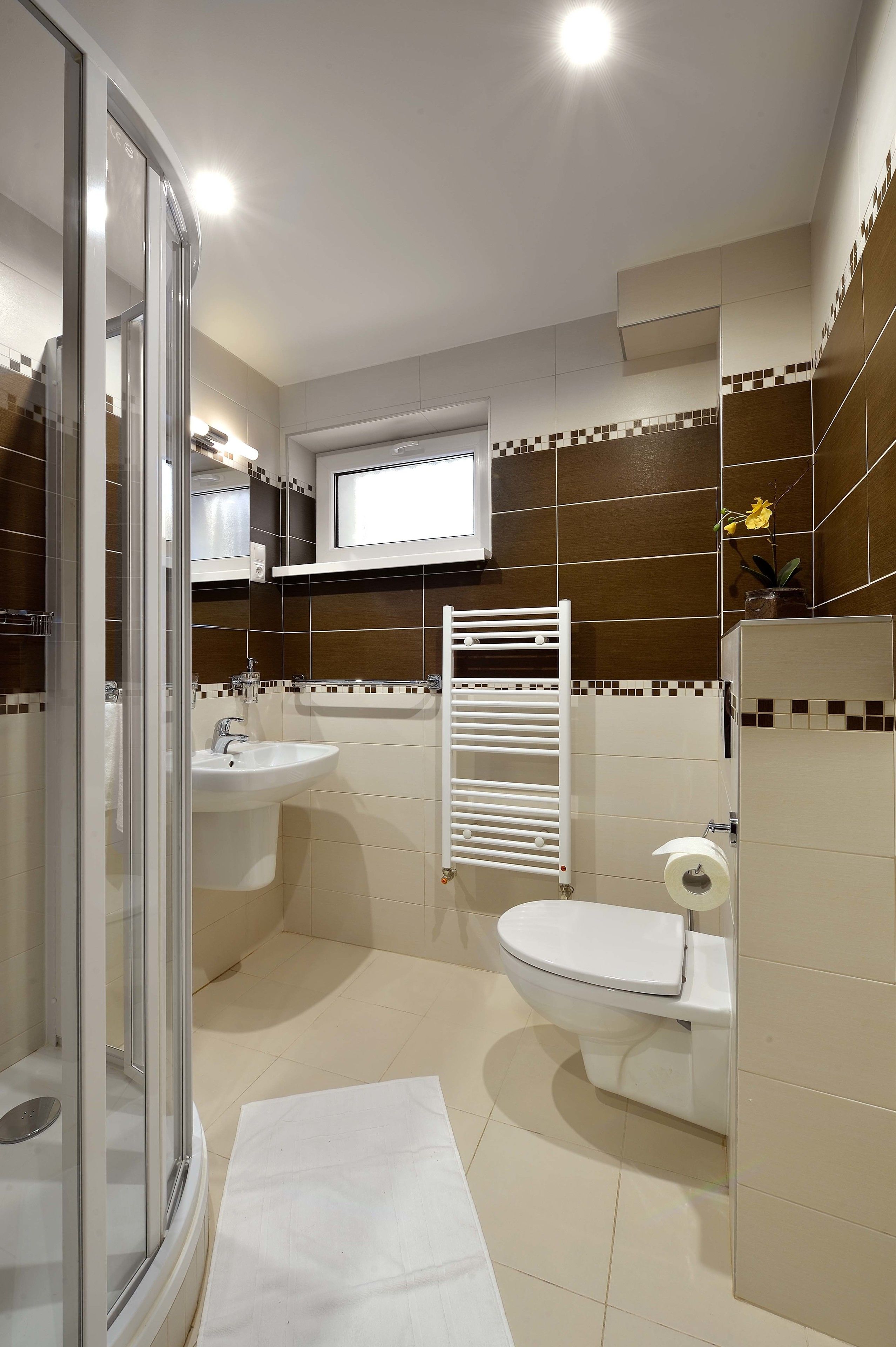 Ein modernes Badezimmer mit einer Duschkabine aus Glas, einem Waschbecken, einer Toilette und einem Handtuchhalter.