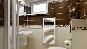 Un baño moderno con cabina de ducha de vidrio, lavamanos, inodoro y toallero.