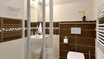 Un baño moderno con cabina de ducha de vidrio, un lavamanos blanco y un inodoro.