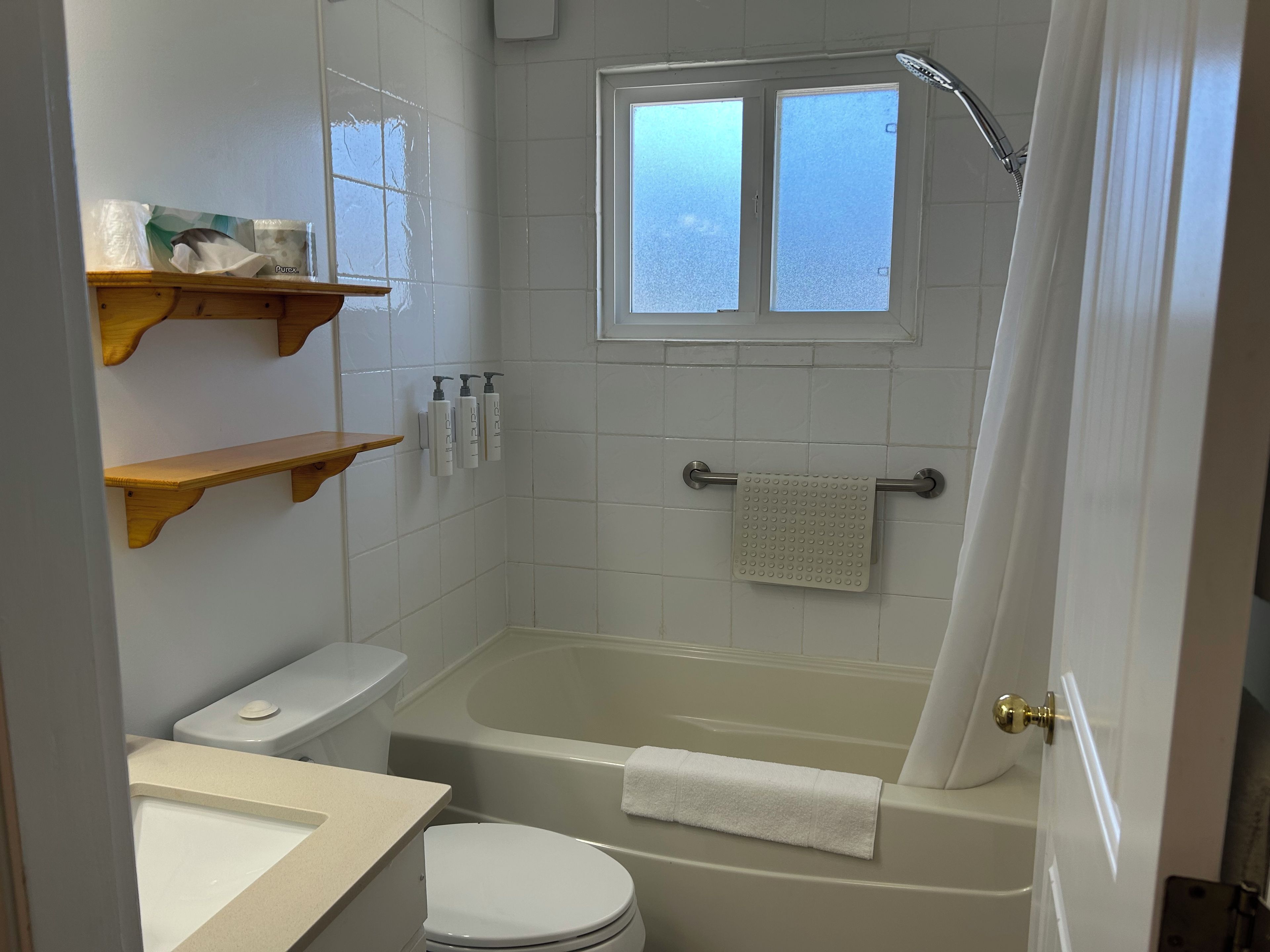 Une salle de bain avec une baignoire, des toilettes et une fenêtre.