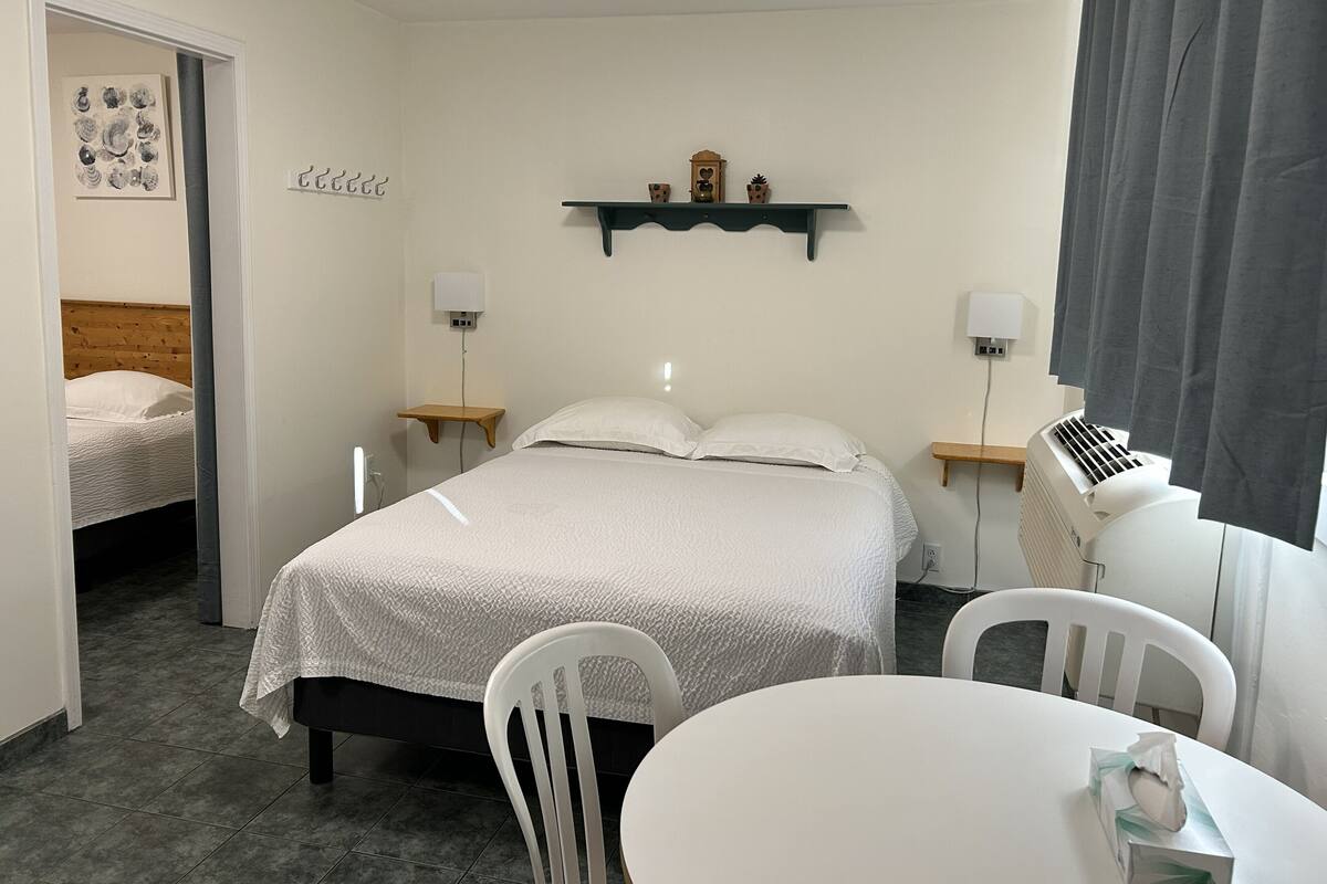 Una habitación de hotel con cama, mesitas de noche, escritorio y sillas.