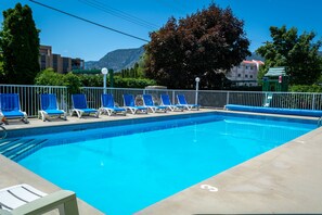 Una piscina al aire libre de temporada, sombrillas