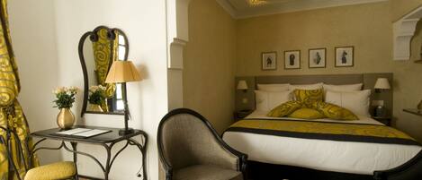 A hotel room with a bed, a chair, a desk, and a mirror.