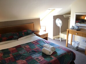 A bedroom with a bed, a desk, a chair, a standing fan, and a window. - Smiths Hotel (Glasgow)