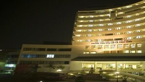 A multi-story hotel with a curved facade, illuminated windows, and a central entrance with a staircase.