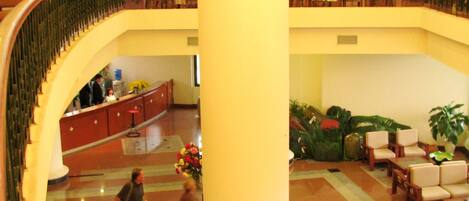 A spacious lobby with a grand staircase, multiple seating areas, and a central column.