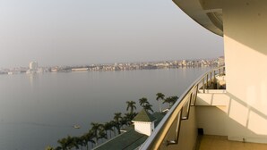 A balcony with a view of a calm river and distant cityscape.