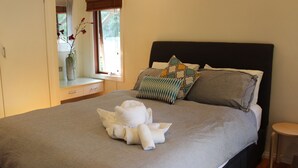 A neatly made bed with a grey bedspread, multiple pillows, and a decorative towel arrangement.