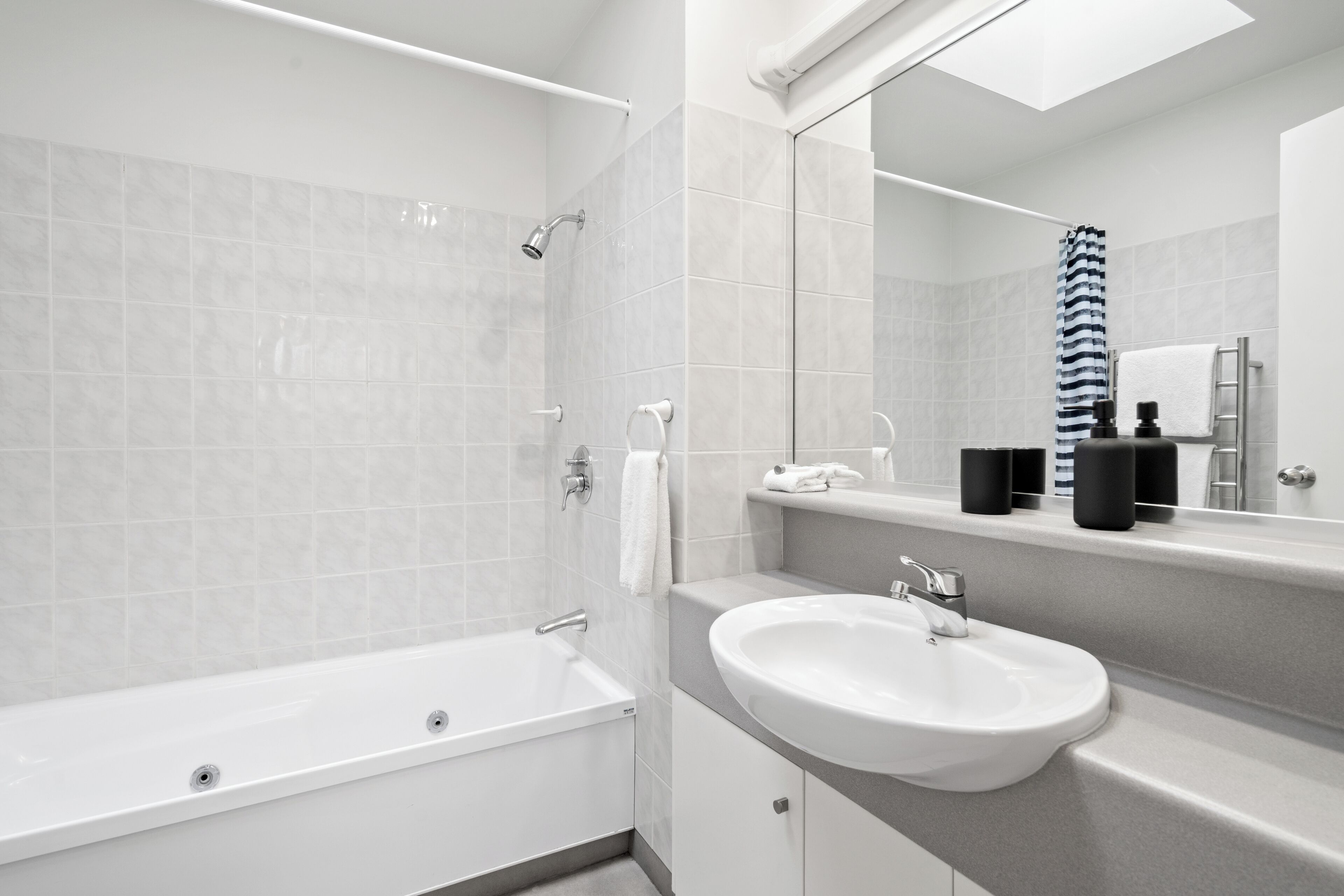 A modern bathroom with a bathtub, a sink, and a mirror.