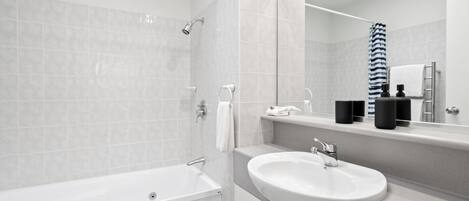 A modern bathroom with a bathtub, a sink, and a mirror.