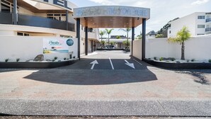 Entrada de un motel con un corredor cubierto, flechas direccionales y un letrero de Pacific Motor Inn.