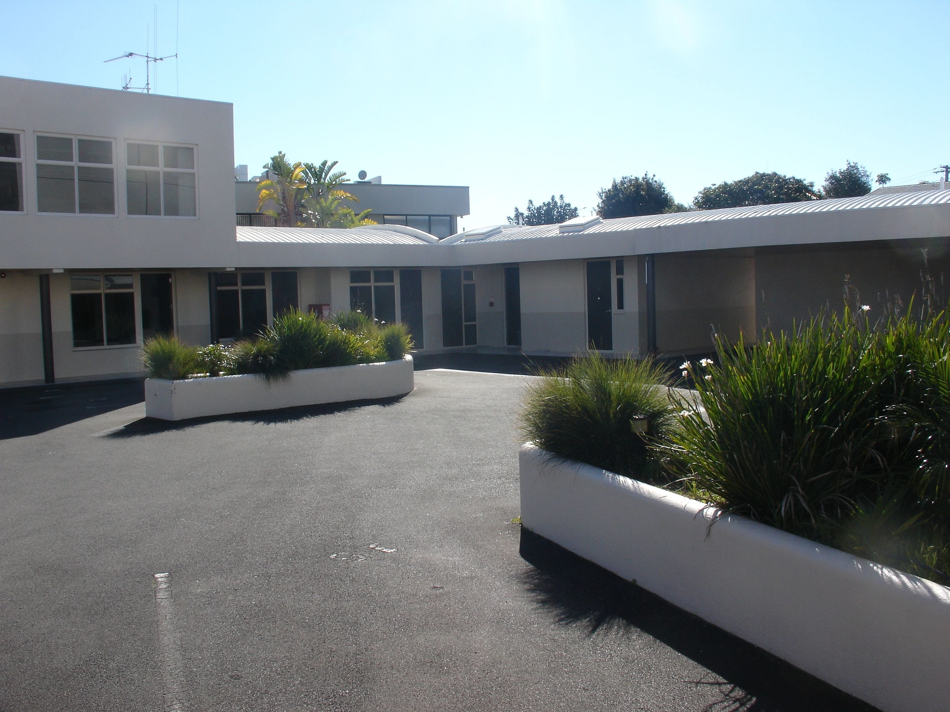 A modern building with a flat roof, large windows, and a central courtyard with planters.