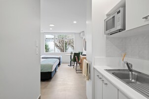 Uma cozinha moderna com micro-ondas embutido, pia e área de refeições com mesa e cadeiras.