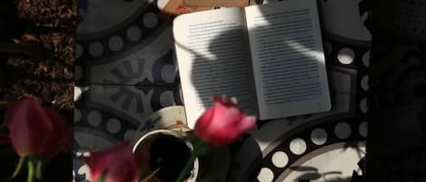 Un libro, una taza y una rosa sobre una mesa estampada.