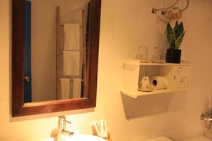 A bathroom with a white sink, mirror, and shelf with toiletries.