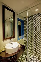 A bathroom with a white sink, a mirror, and a shower with a glass door.