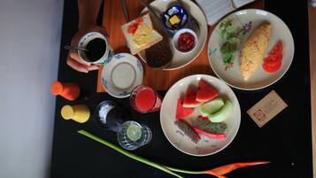 Una mesa con diversos alimentos y condimentos, como tostadas, una tortilla, sandía y un plato con fruta.