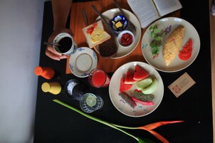 Een tafel met diverse etenswaren en toevoegingen, waaronder toast, een omelet, watermeloen en een bord met fruit.