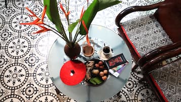 Ein runder Glastisch mit einer roten Schüssel, einem kleinen Blumenvasen mit Pflanze, einer Kaffeetasse und einem Teller mit Snacks.