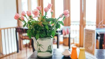 Une table avec un vase de roses roses, une théière et des condiments.