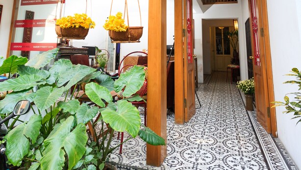A multi-level interior with a tiled floor, wooden balconies, and potted plants. - Maison d'Orient Hotel (Hanoi)
