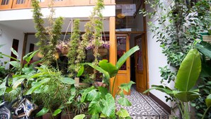 A courtyard with potted plants, a motorcycle, and a door leading to a building. - Maison d'Orient Hotel (Hanoi)