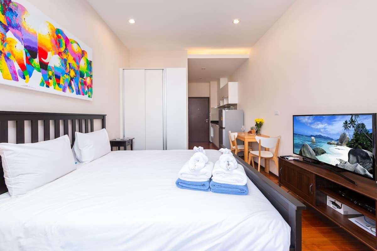Une chambre d’hôtel avec un lit, une télévision, un bureau avec une chaise, un tableau au mur et une vue sur l’océan.