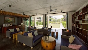 A modern lounge area with sofas, a coffee table, and a bookshelf. - The Title Condo by TropicLook (Rawai)