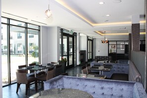 A modern interior with a seating area, tables, and a fireplace. - Holiday Inn Carlsbad by IHG (Carlsbad)