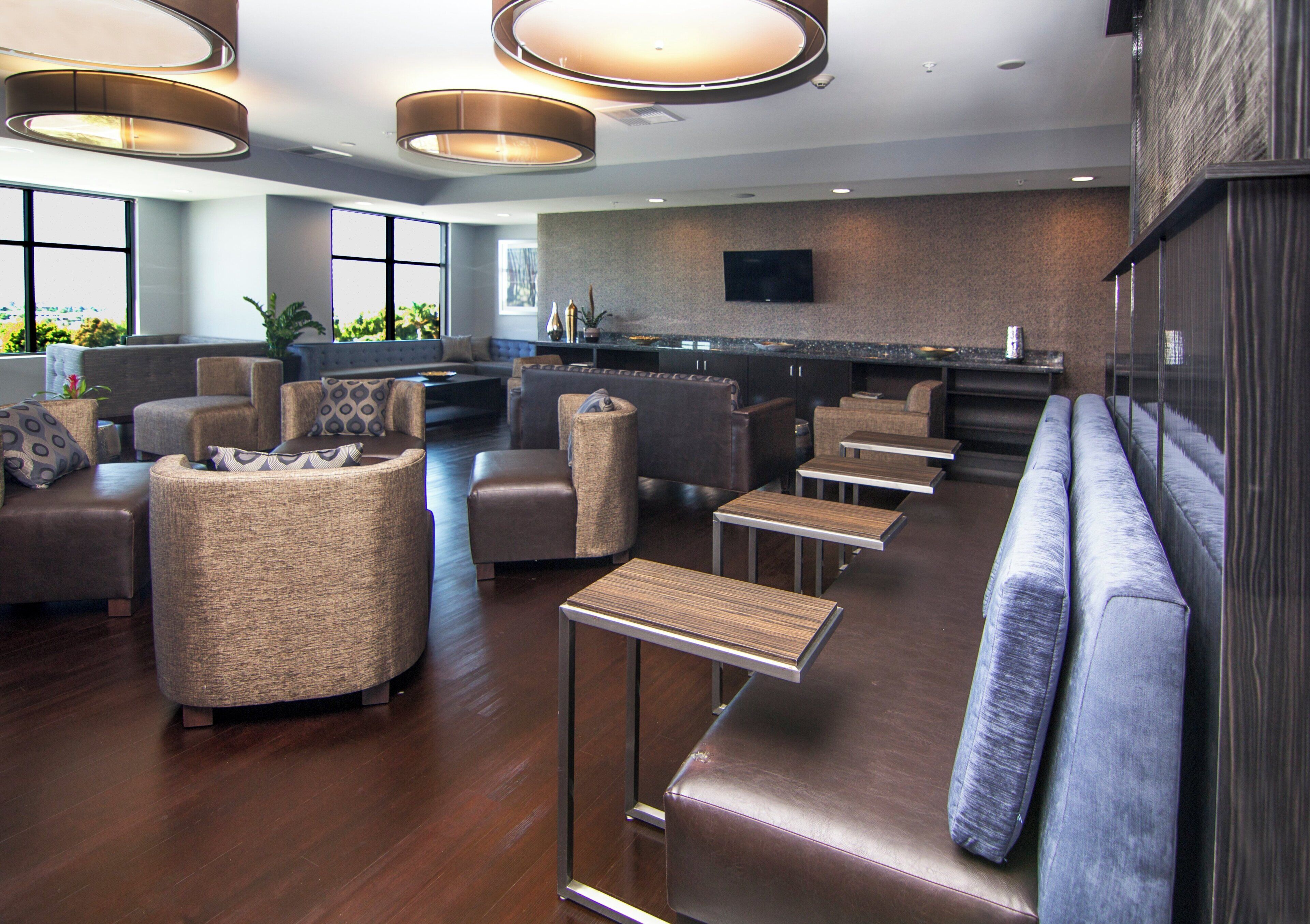 A modern lounge area with sofas, a bar, and a television.
