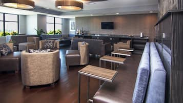 A modern lounge area with sofas, a bar, and a television.