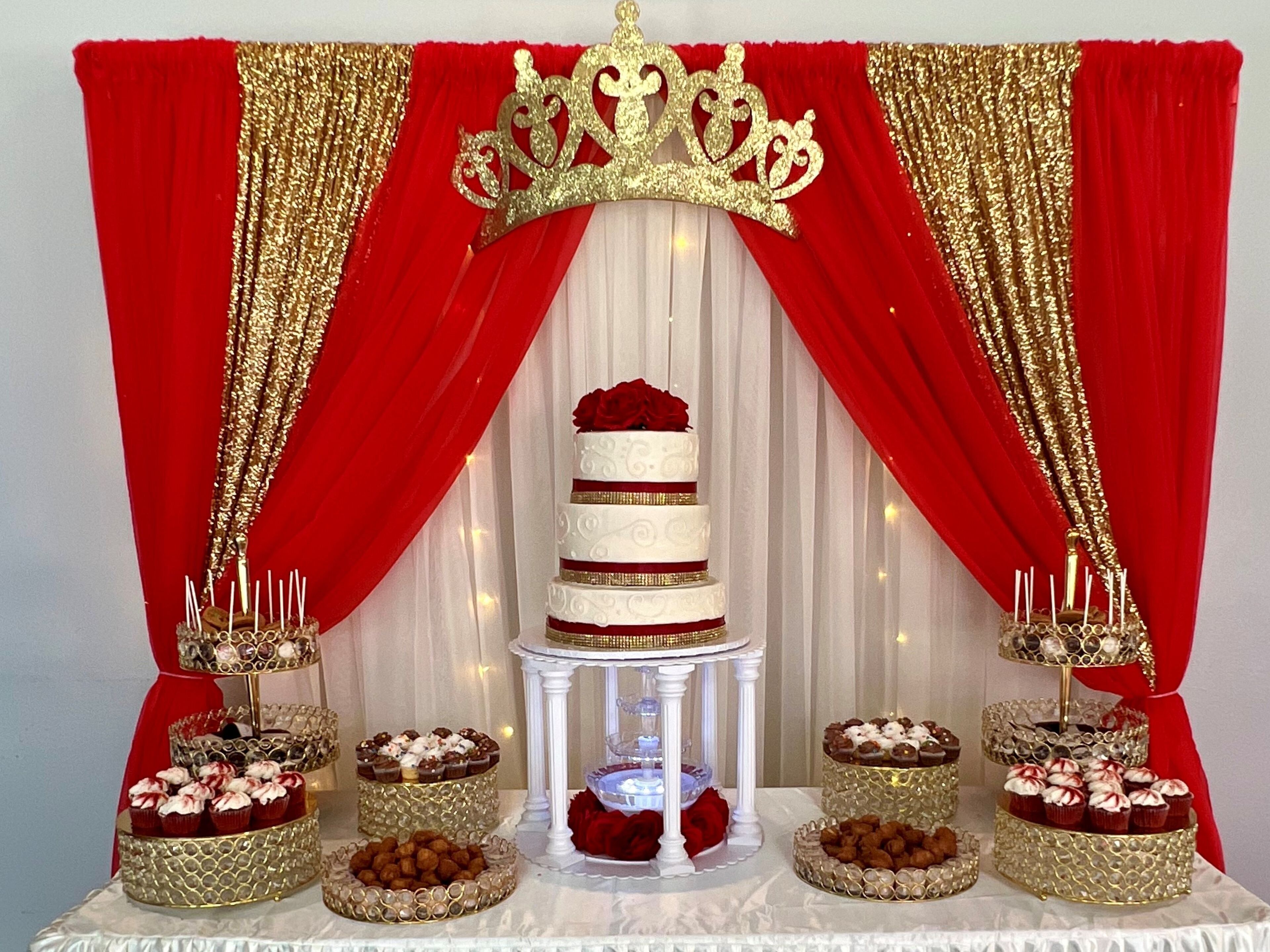 Eine gestufte Hochzeitstorte mit goldener Krone, umgeben von Desserttischen mit Cupcakes und Pralinen.