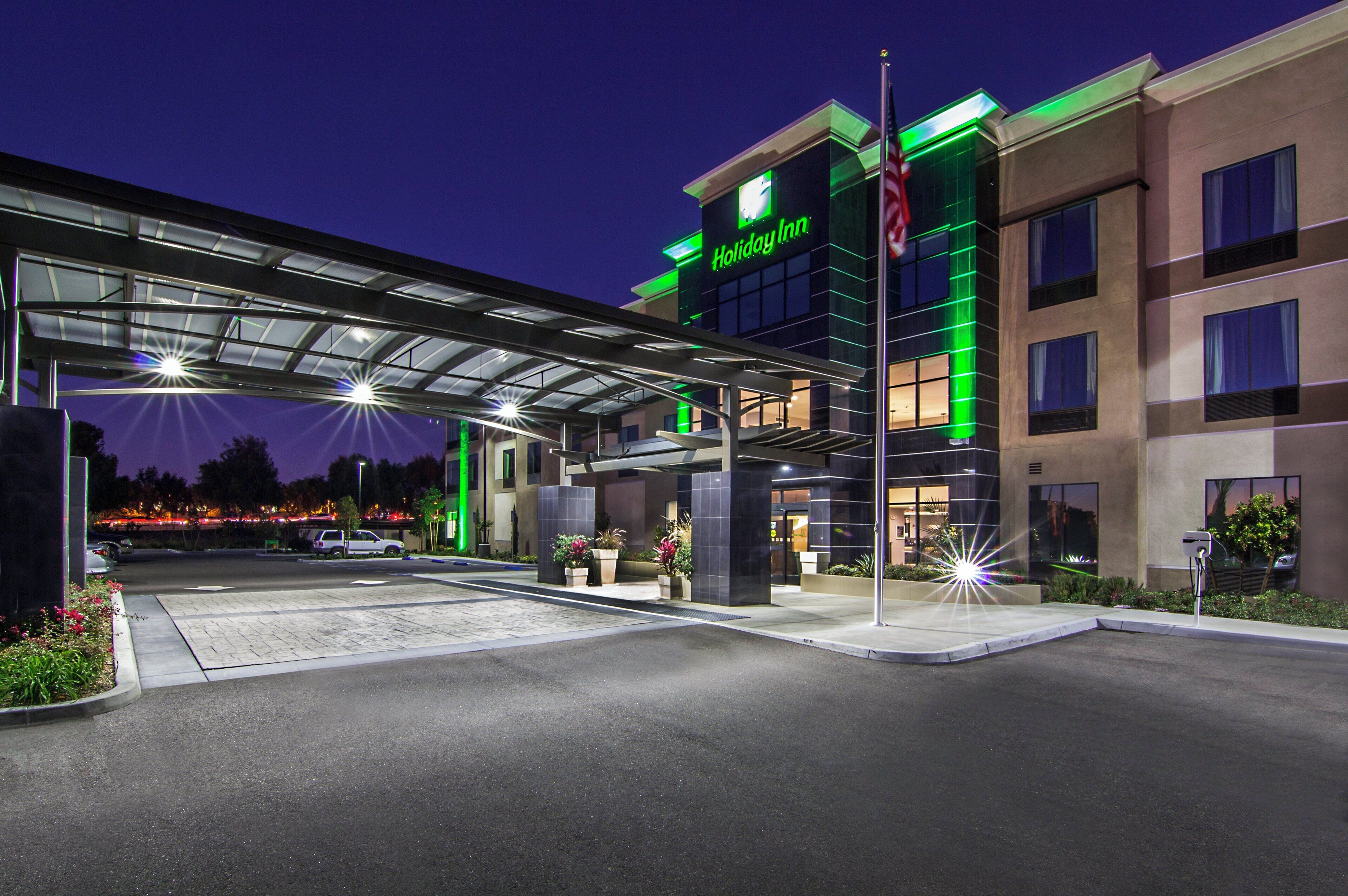 A Holiday Inn hotel with a covered entrance, outdoor parking, and a well-lit facade.