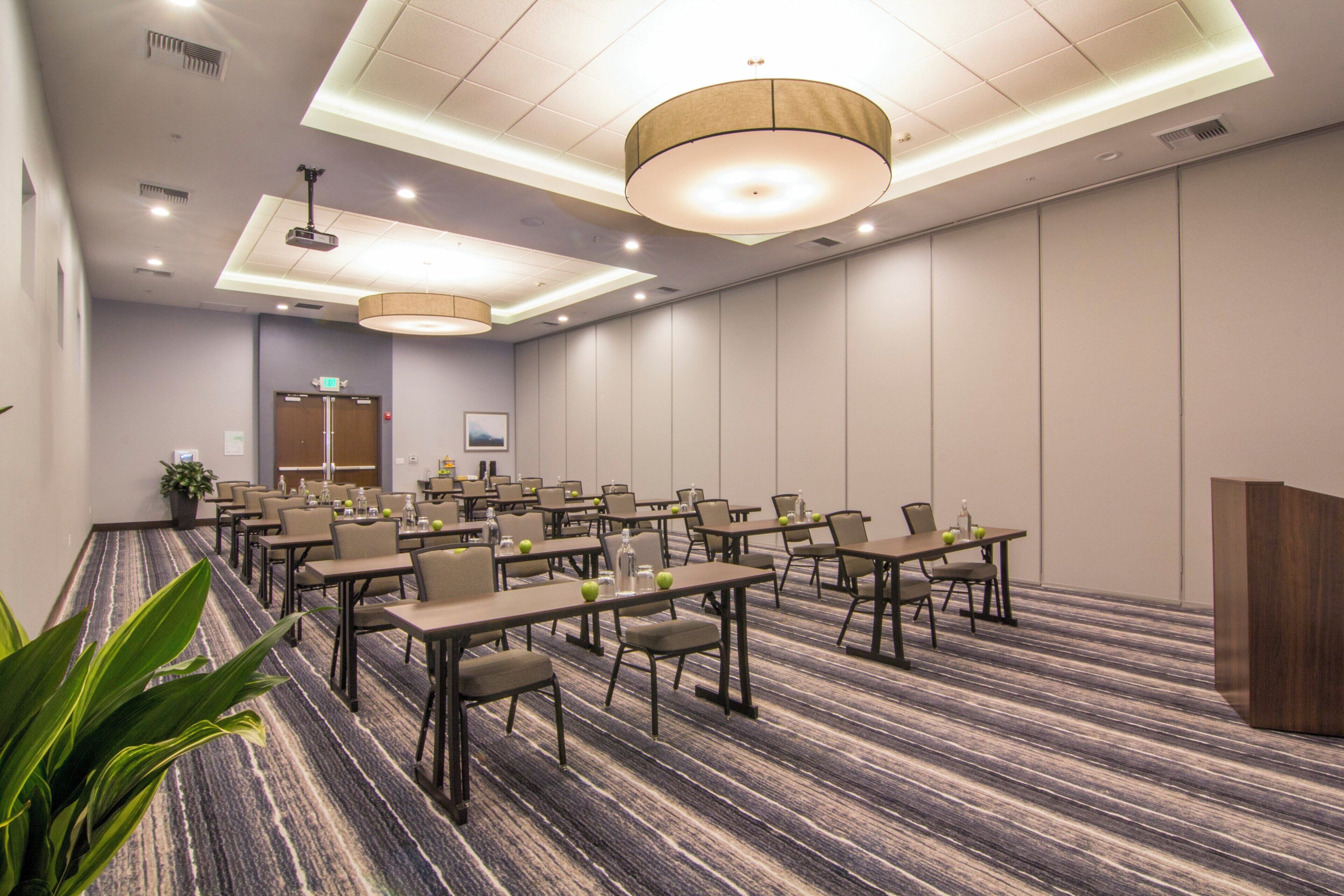 A conference room with tables and chairs, a podium, and a carpeted floor.
