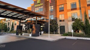 A Holiday Inn hotel with a modern design, featuring a covered entrance and a flagpole. - Holiday Inn Carlsbad by IHG (Carlsbad)