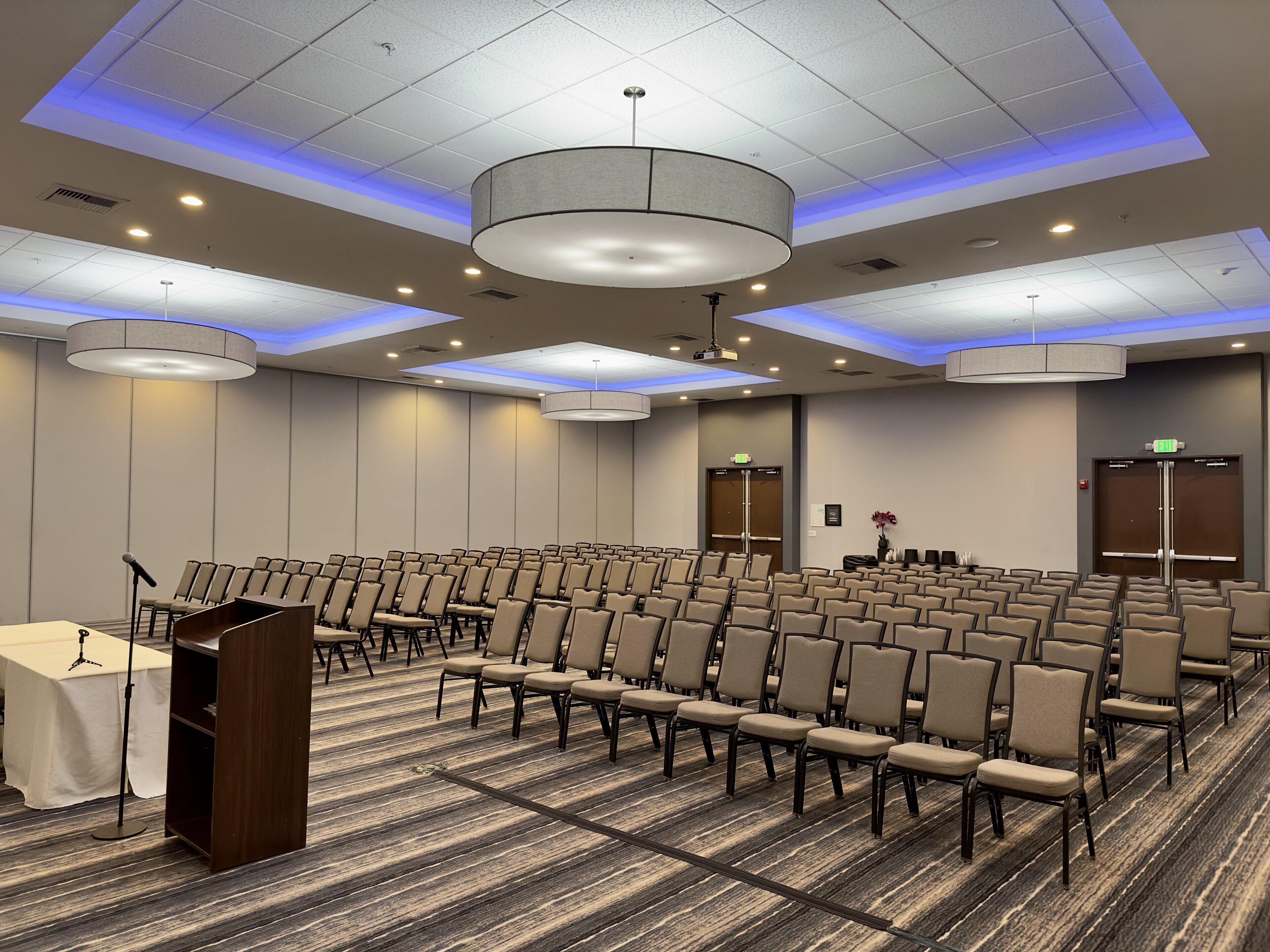 A conference room with rows of chairs, a podium, and a carpeted floor.