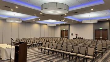 A conference room with rows of chairs, a podium, and a carpeted floor.