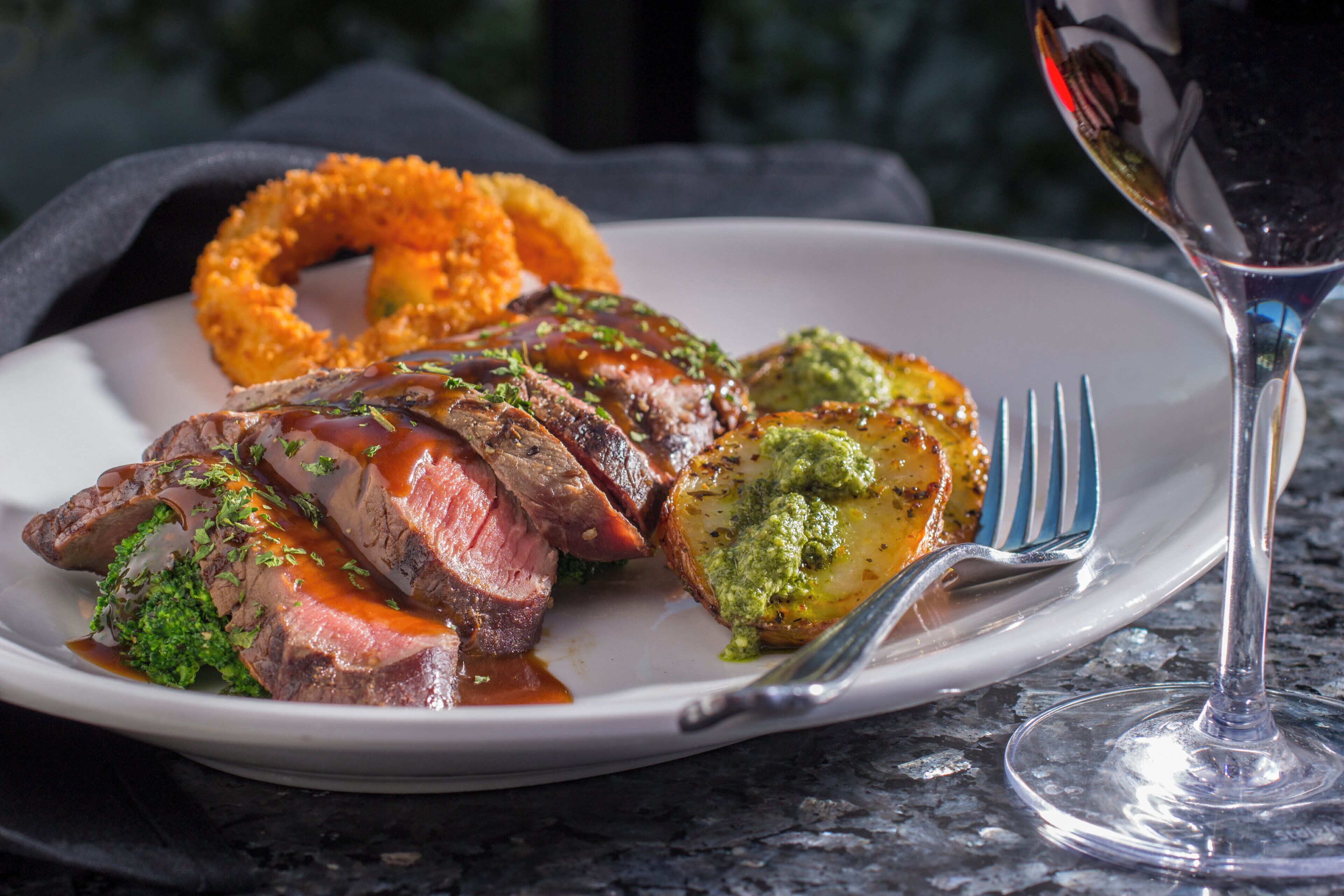 Ein Teller mit Steak, Brokkoli und Zwiebelringen.