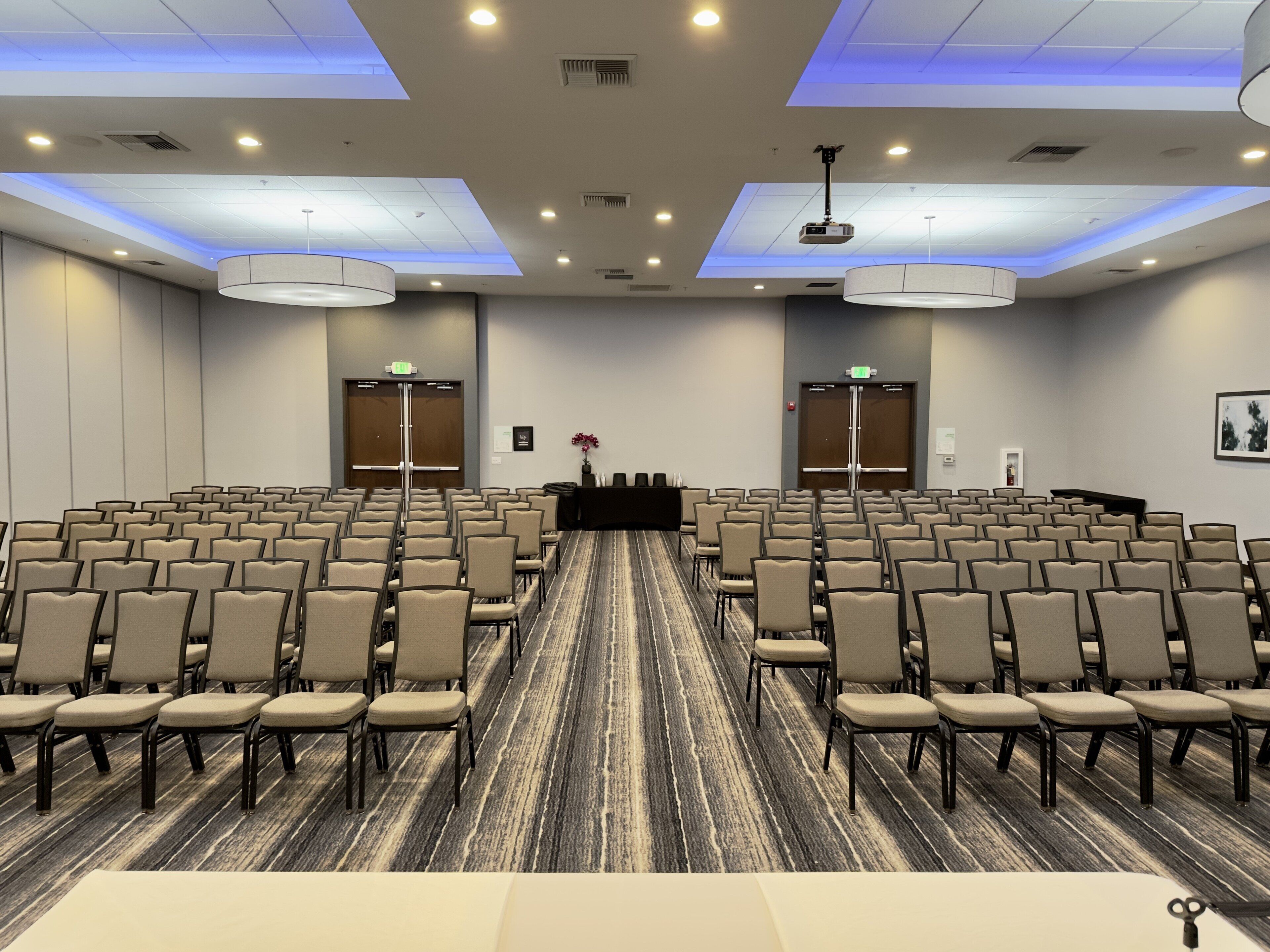 A conference room with rows of chairs, a podium, and a carpeted floor.