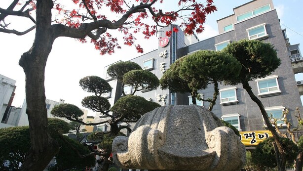 A stone elephant sculpture in a garden with trees and a building in the background. - Andong Hotel (Andong)
