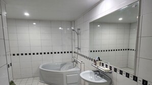 A modern bathroom with a freestanding bathtub, a pedestal sink, and a large mirror. - Andong Hotel (Andong)