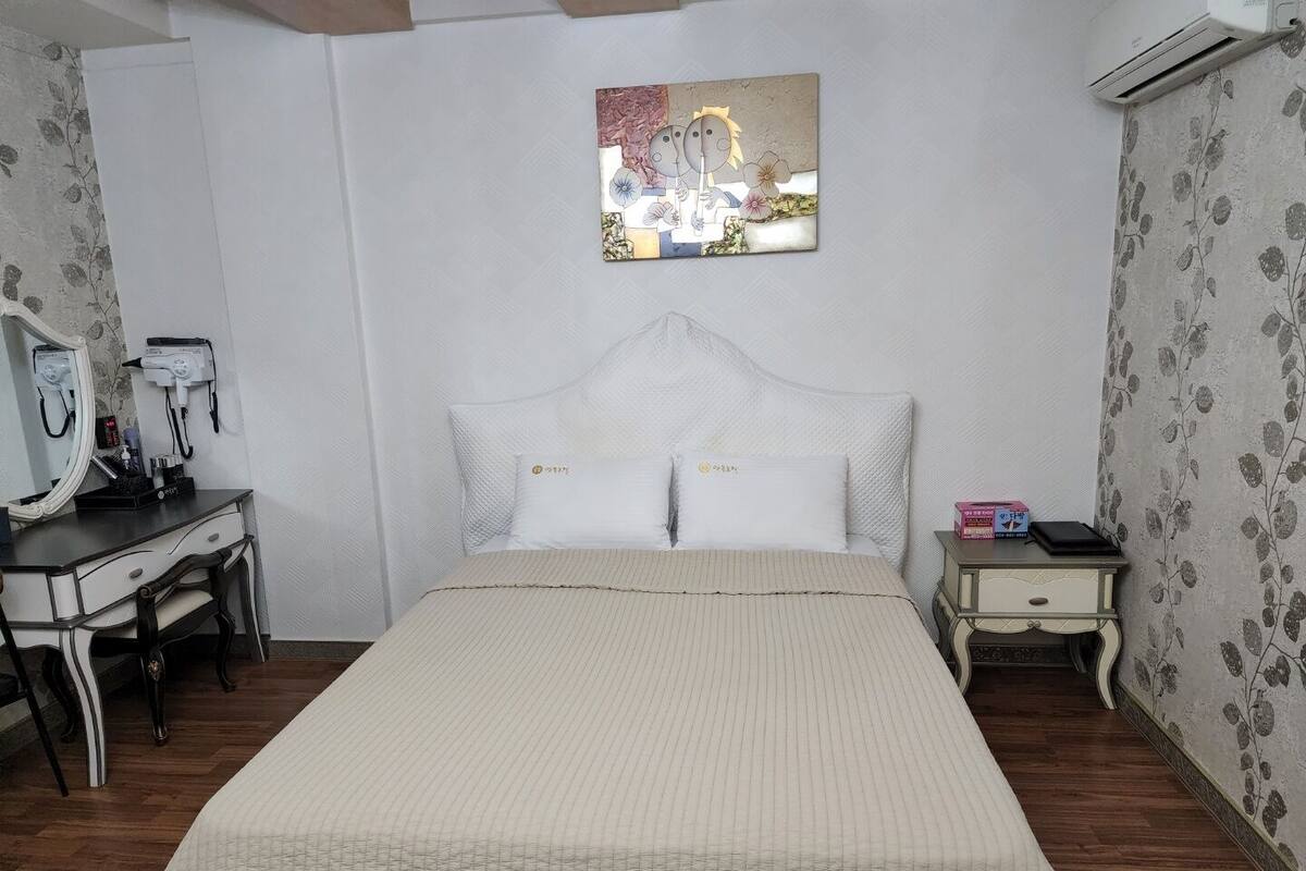 Habitación de hotel con cama, escritorio con espejo, silla y aire acondicionado.