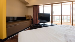 A hotel room with a bed, a television on a stand, a sofa, and a large window with a view. - New Town Suites at Bandar Sunway (Petaling Jaya)