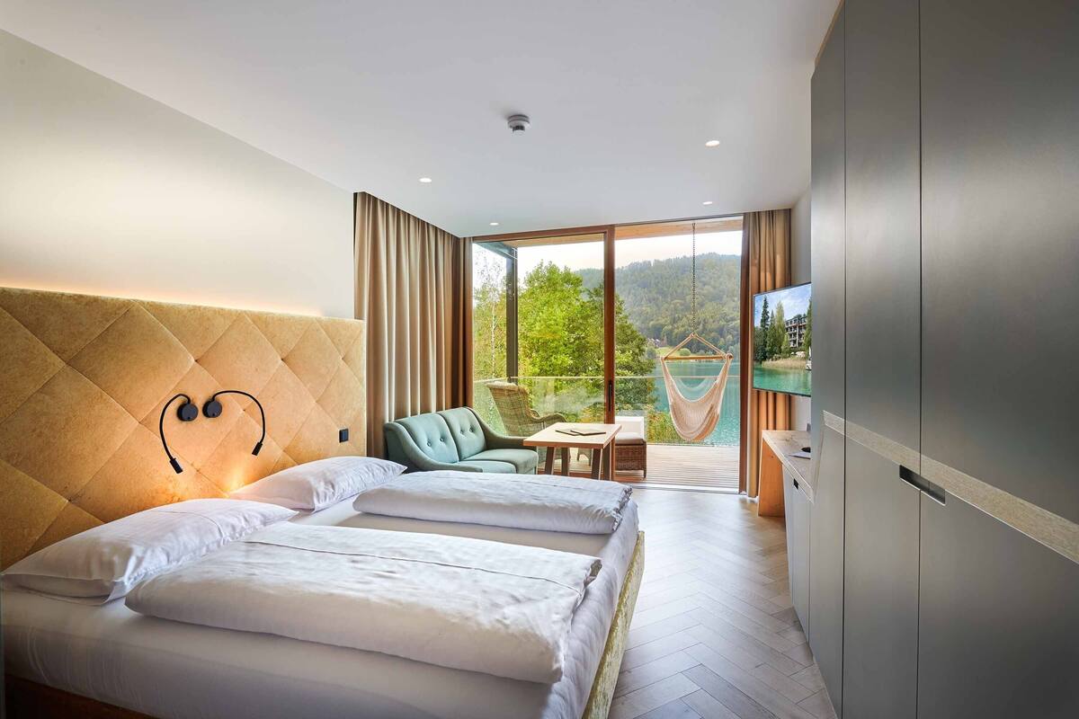 Una habitación de hotel con una cama grande, vistas al exterior, un televisor y un balcón con una hamaca.
