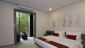 Moderni hotellihuone, jossa on suuri sänky, lasiovesta avautuva näkymä ja seinä, jossa on ihmisiä esittävä viivapiirros.