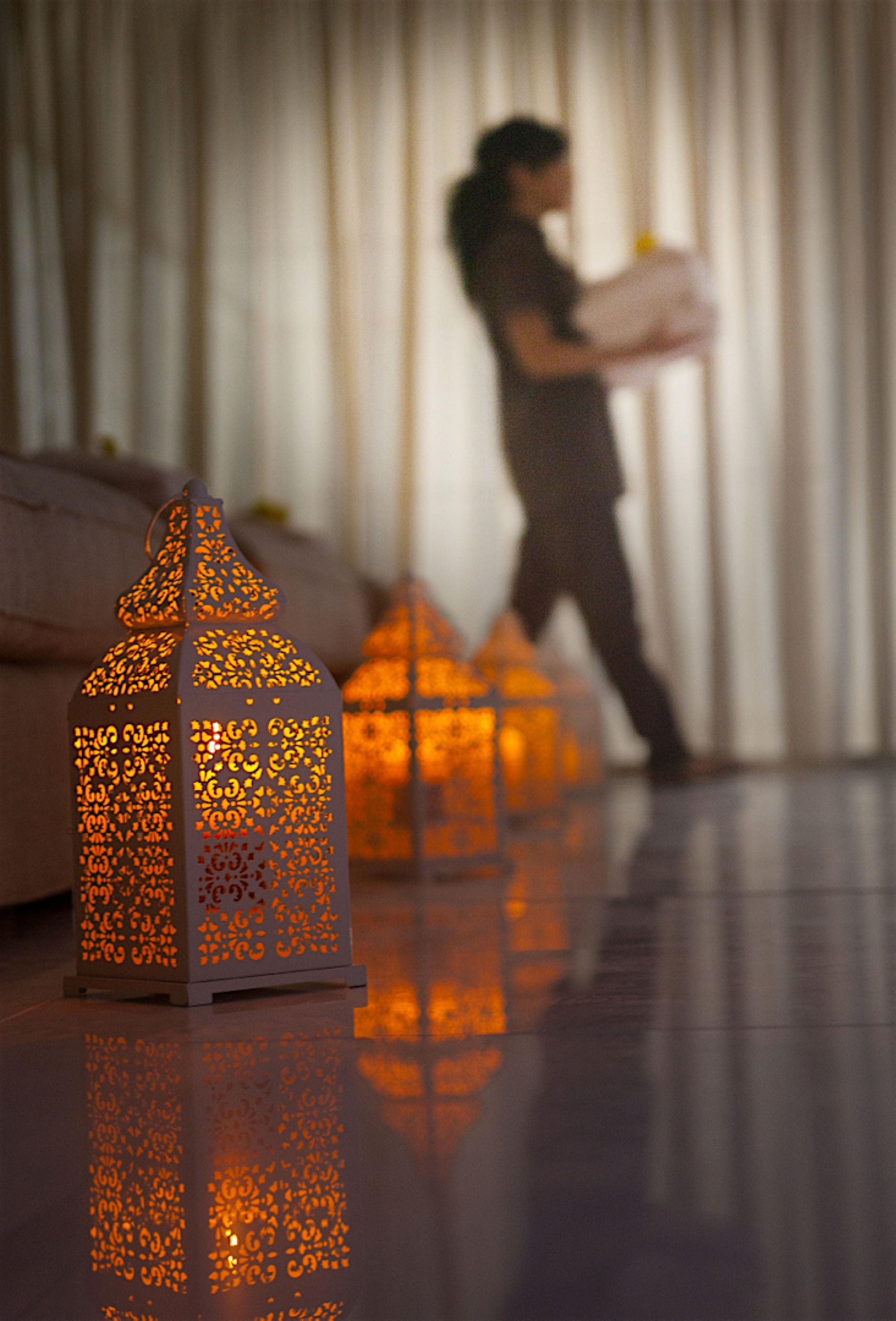 A room with a reflective floor, a person in the background, and decorative lanterns.