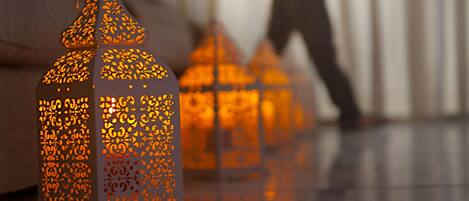 A room with a reflective floor, a person in the background, and decorative lanterns.