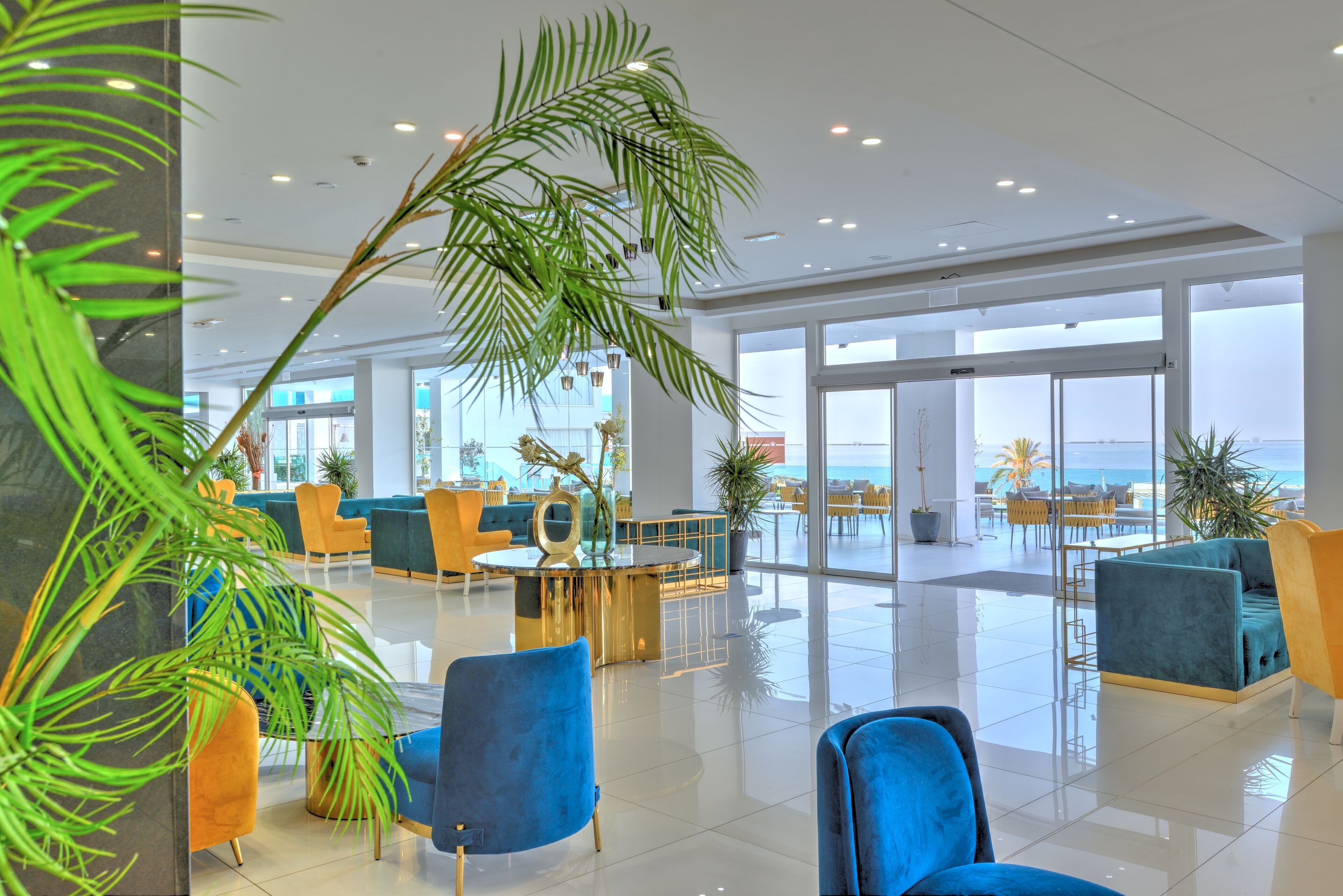 A spacious lobby with a view of the sea, featuring modern furniture and large windows.